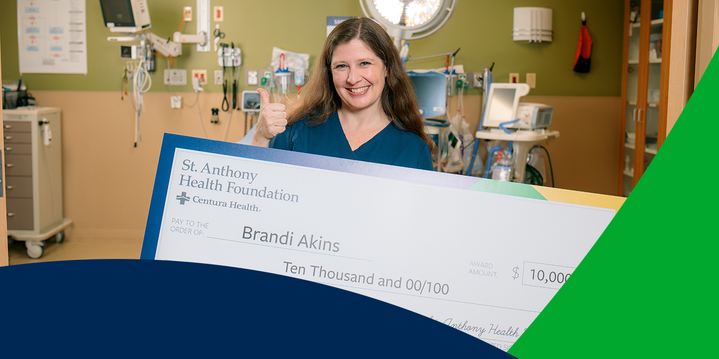 St. Anthony Hospital Foundation scholarship recipient holding giant check and smiling