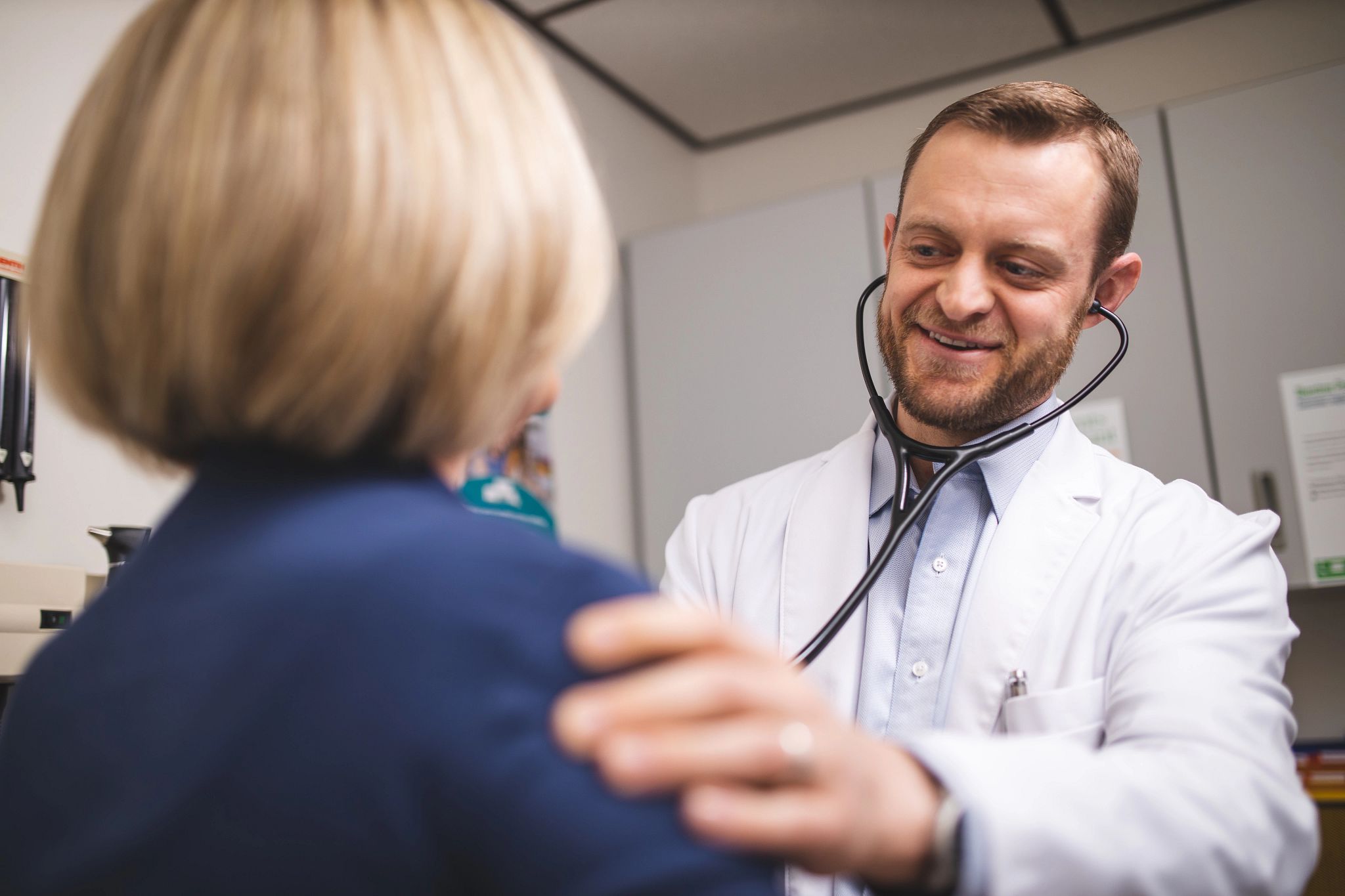 Smiling physician checking heartbeat of patient